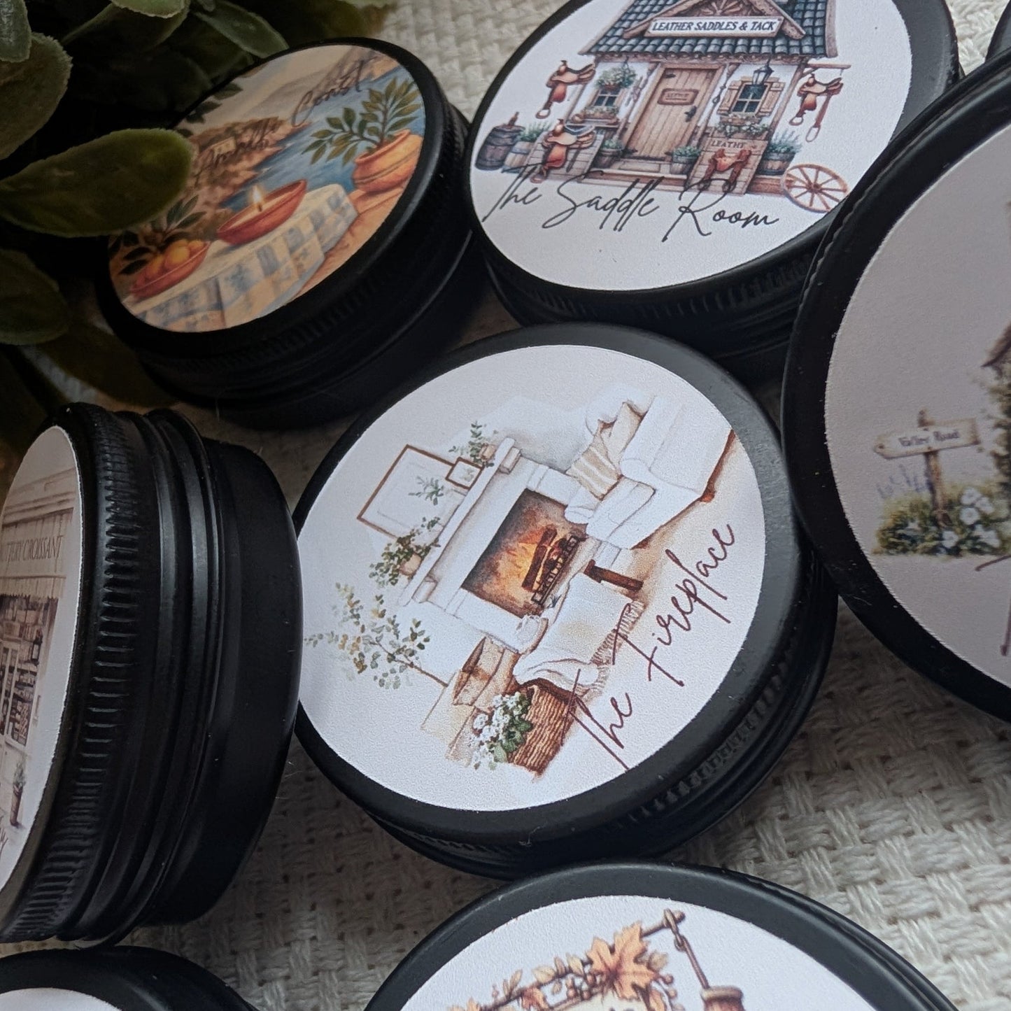 Collection of decorative containers with illustrated lids featuring scenes and text containing wax melts.