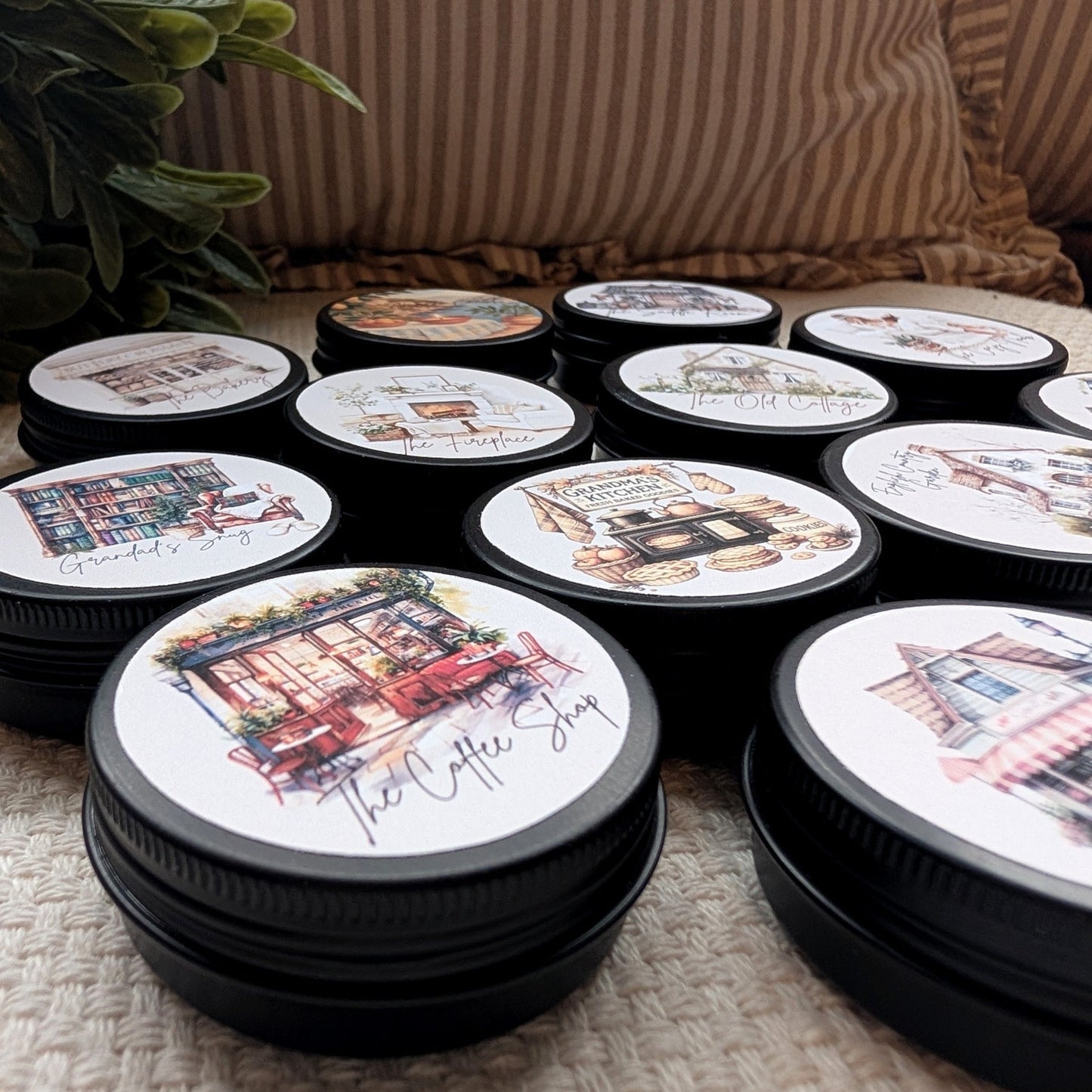 Set of round tins with artistic designs on a textured surface containing wax melts.