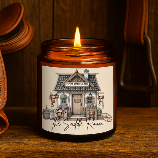 Candle in a jar with 'The Saddle Room' label on a wooden surface